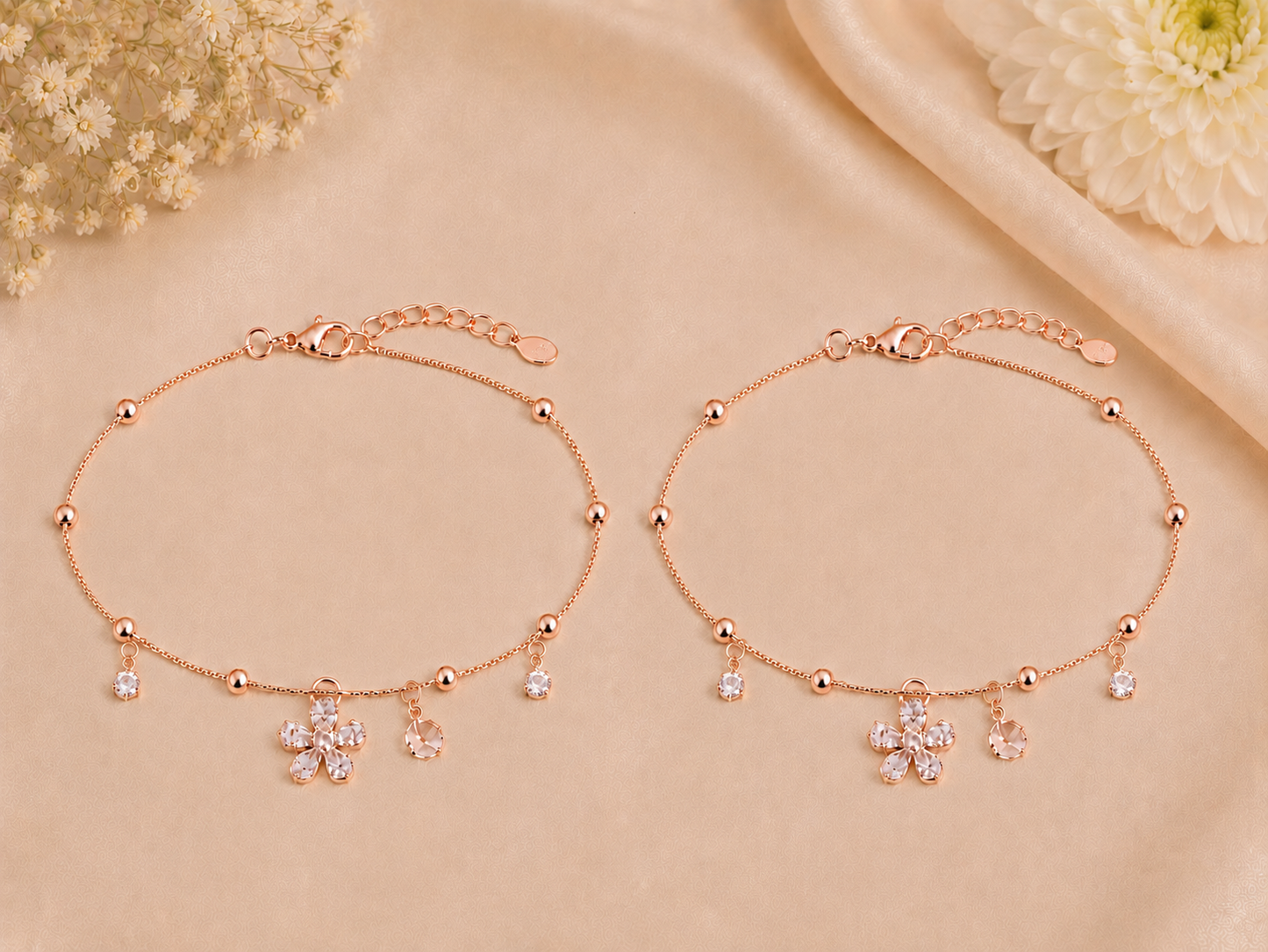 Rose gold bracelet with floral charms on a beige background