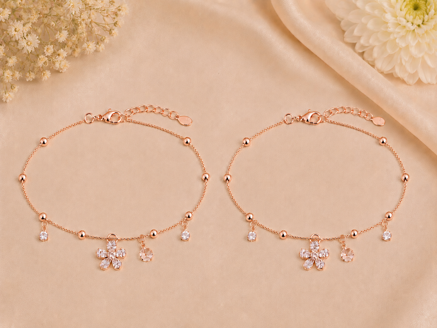 Rose gold bracelet with floral charms on a beige background
