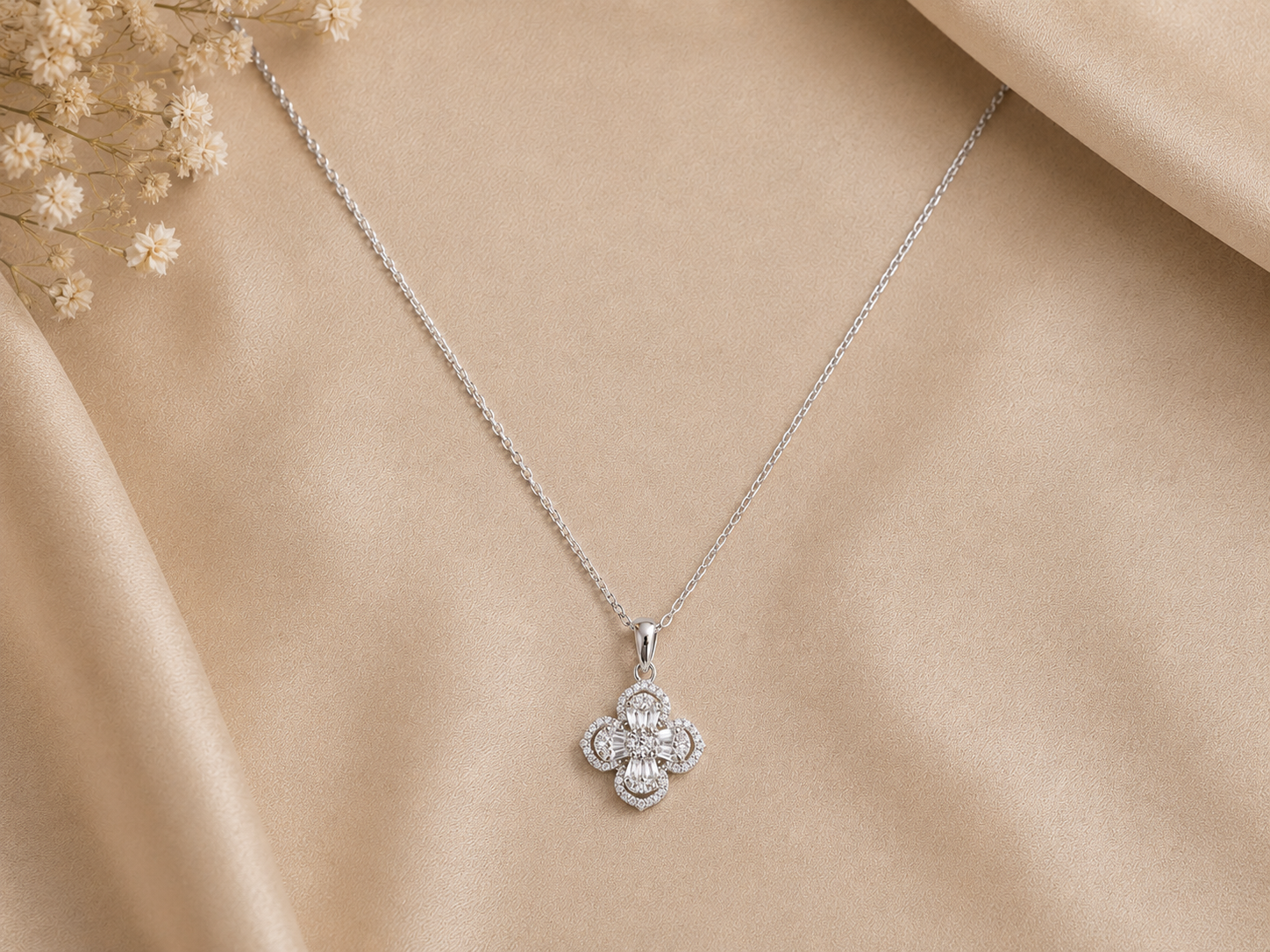 Silver necklace with a clover-shaped pendant on a beige fabric background