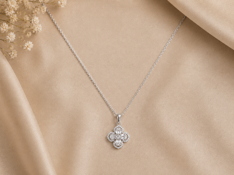 Silver necklace with a clover-shaped pendant on a beige fabric background