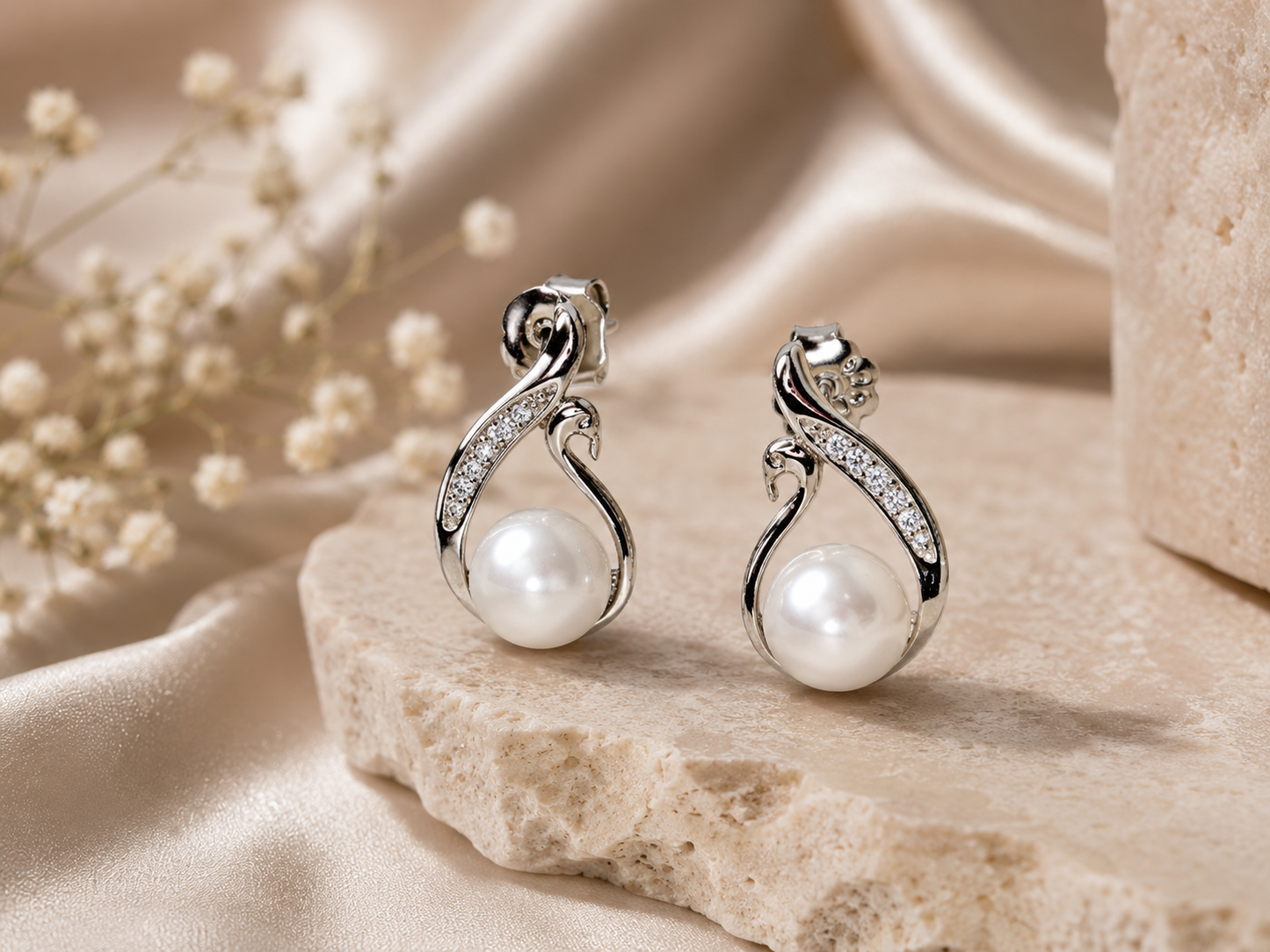 Pearl earrings with silver fixtures on a beige fabric background