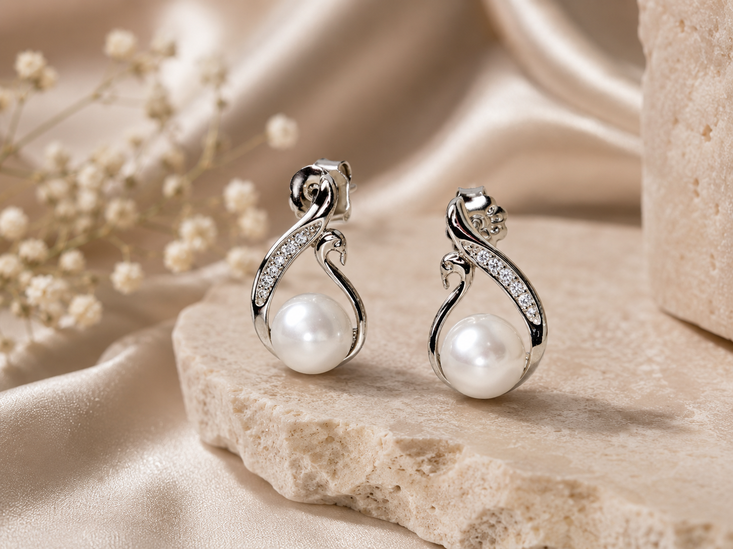 Pearl earrings with silver fixtures on a beige fabric background