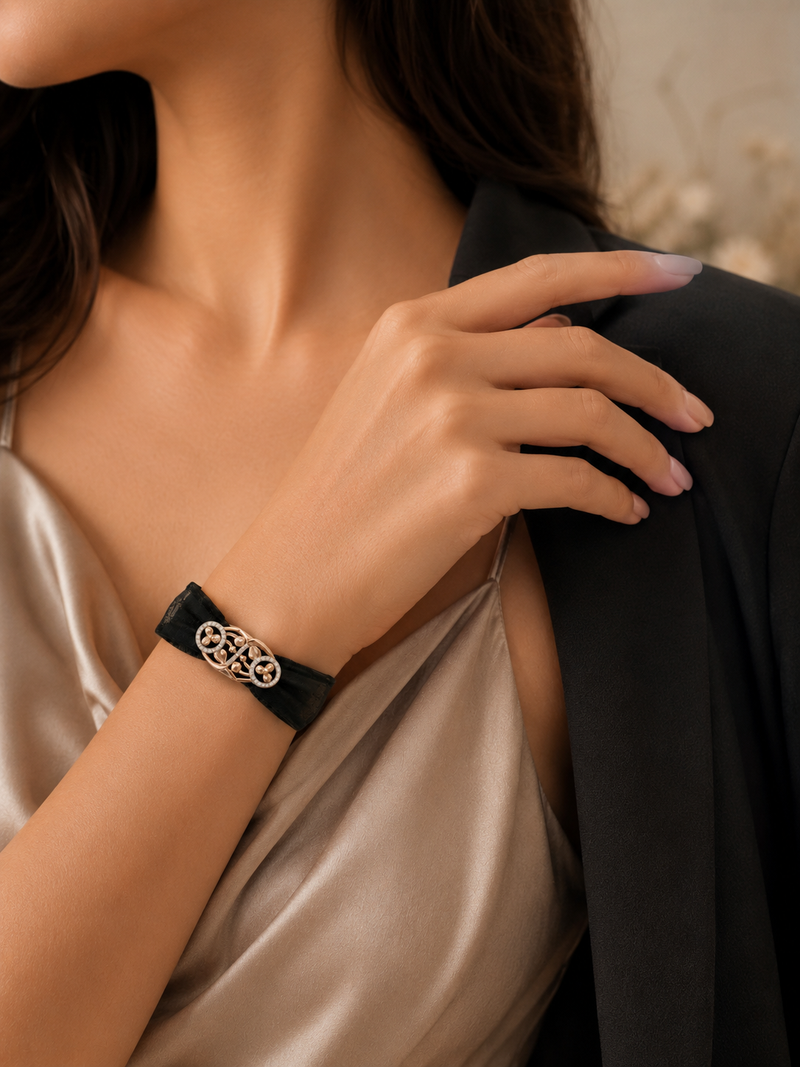Close-up of a person wearing a black bracelet with a intricate design on their wrist.
